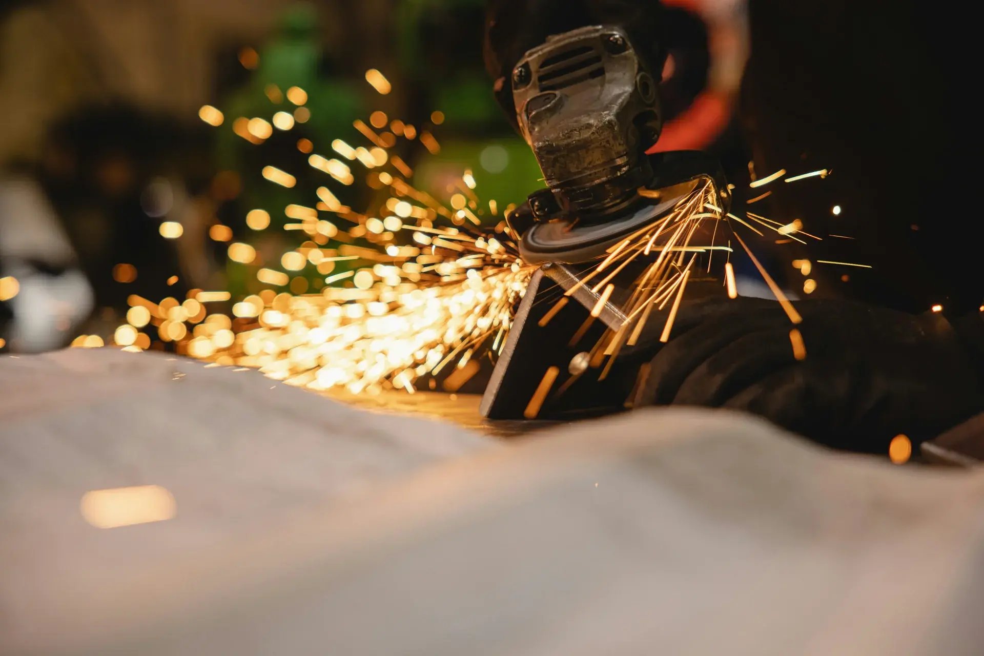 Close-up of an angle grinder cutting metal with a bright shower of sparks in a workshop.