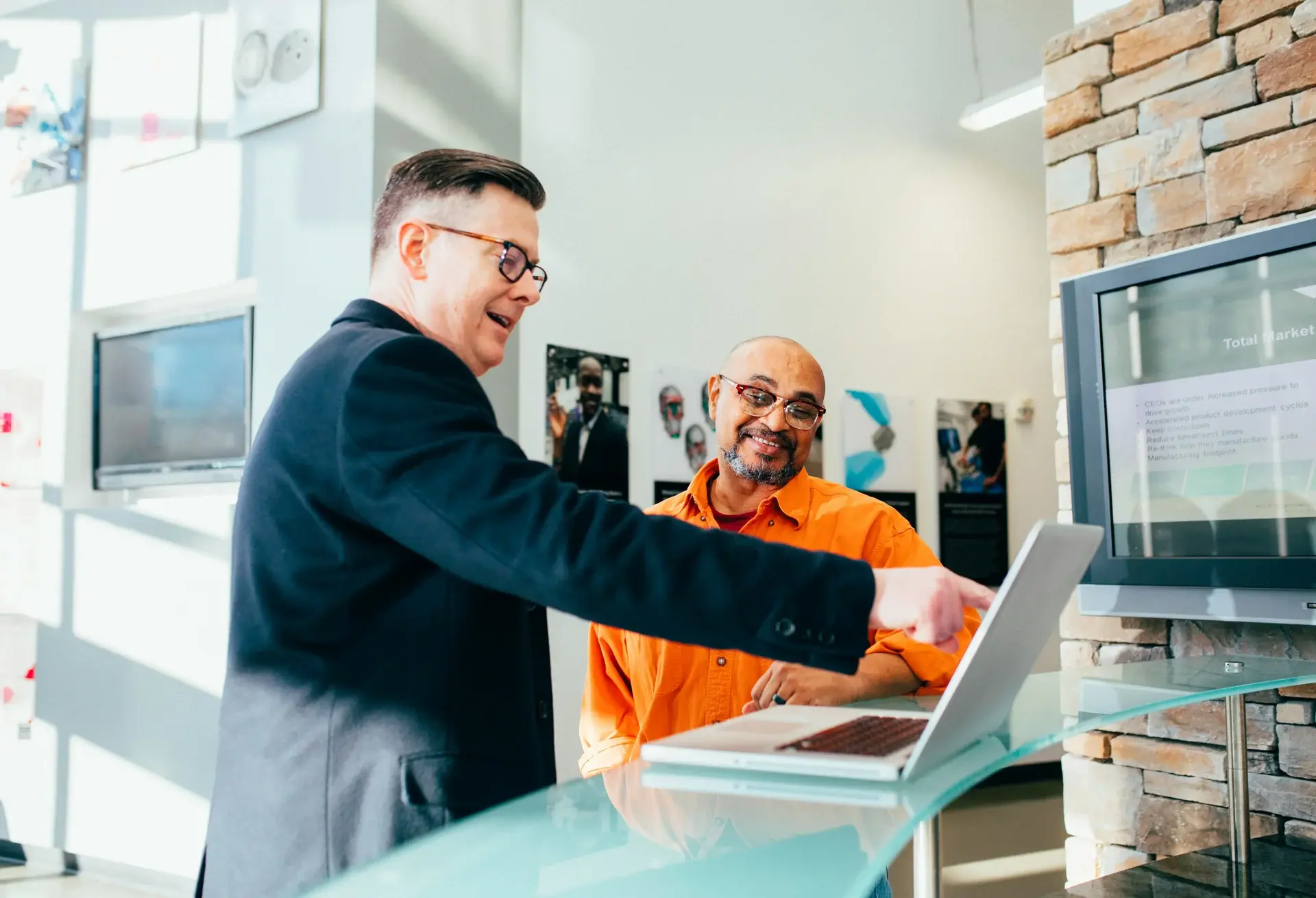 Two business professionals collaborating over a laptop in a modern office during a strategy discussion.