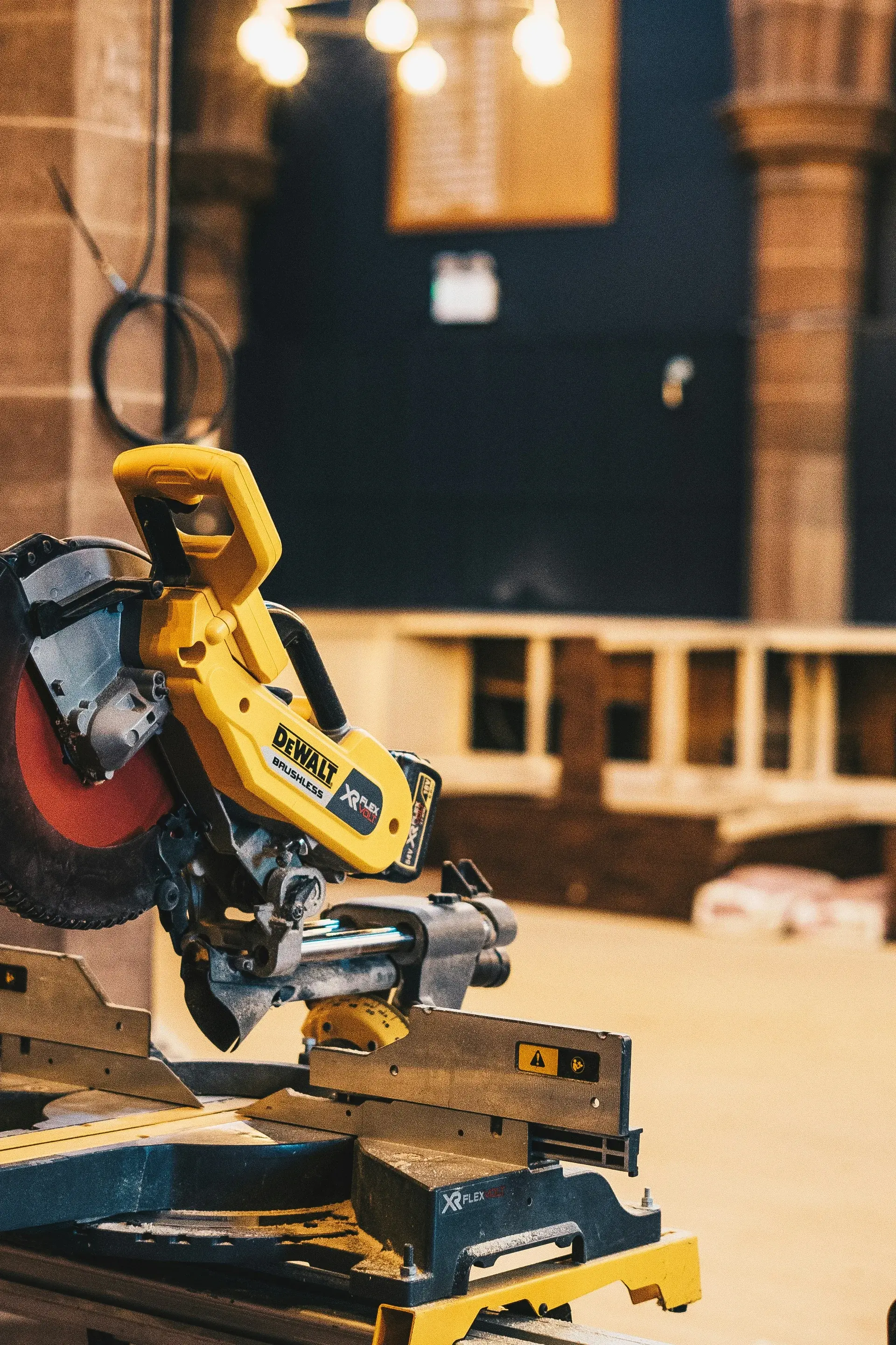 Cordless brushless miter saw mounted on a stand at an interior construction jobsite.