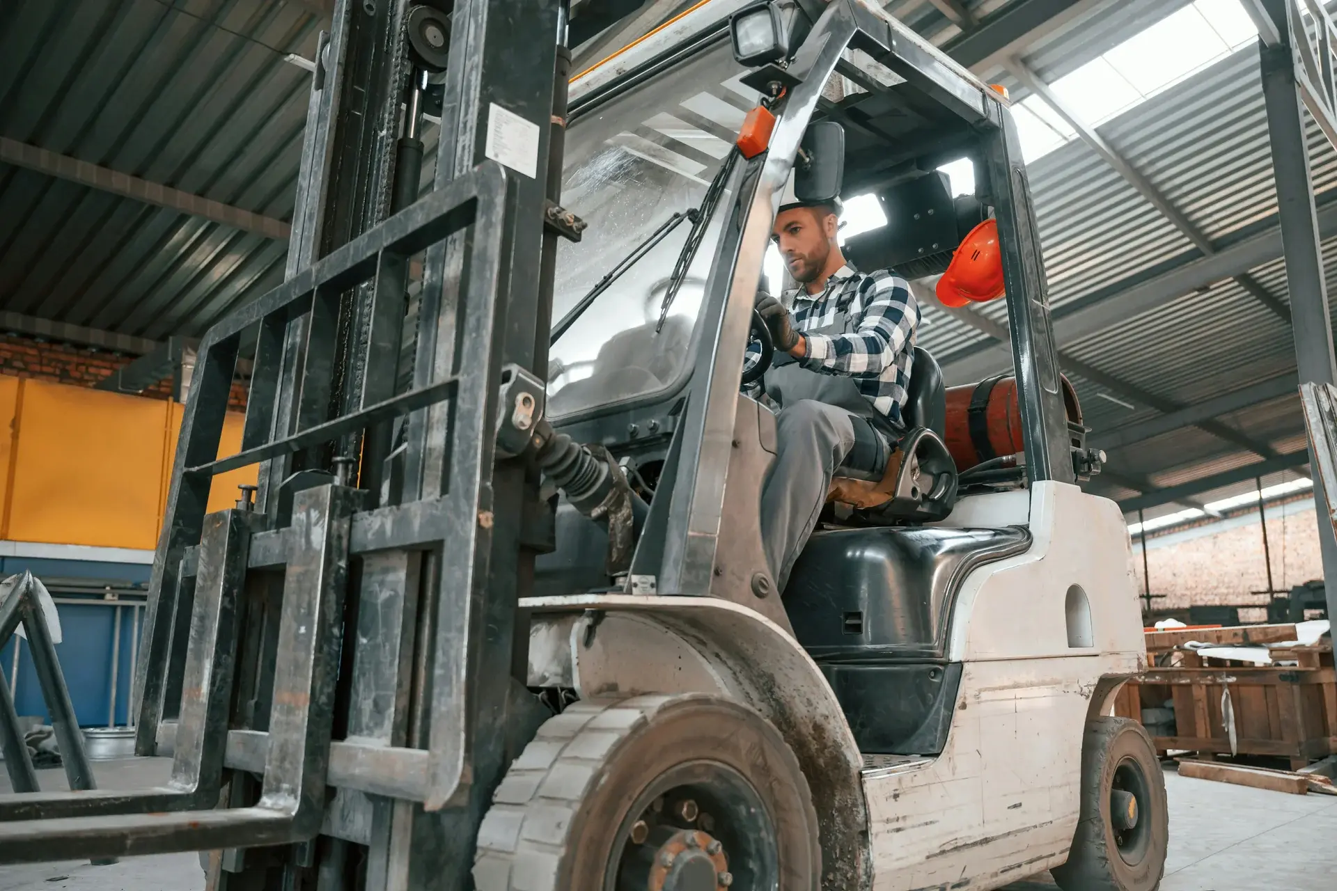 Forklift operator driving a propane forklift inside an industrial warehouse facility.