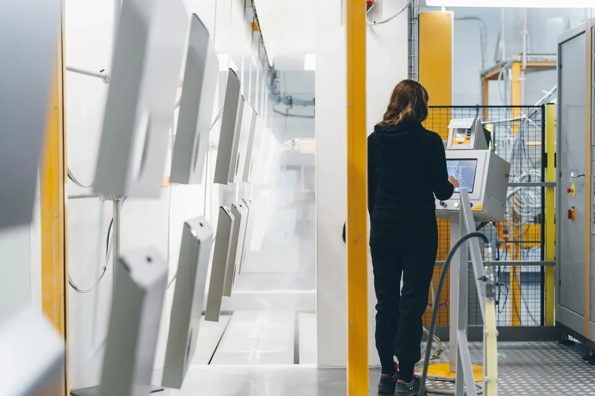 Manufacturing technician operating a control panel on an automated industrial production line.